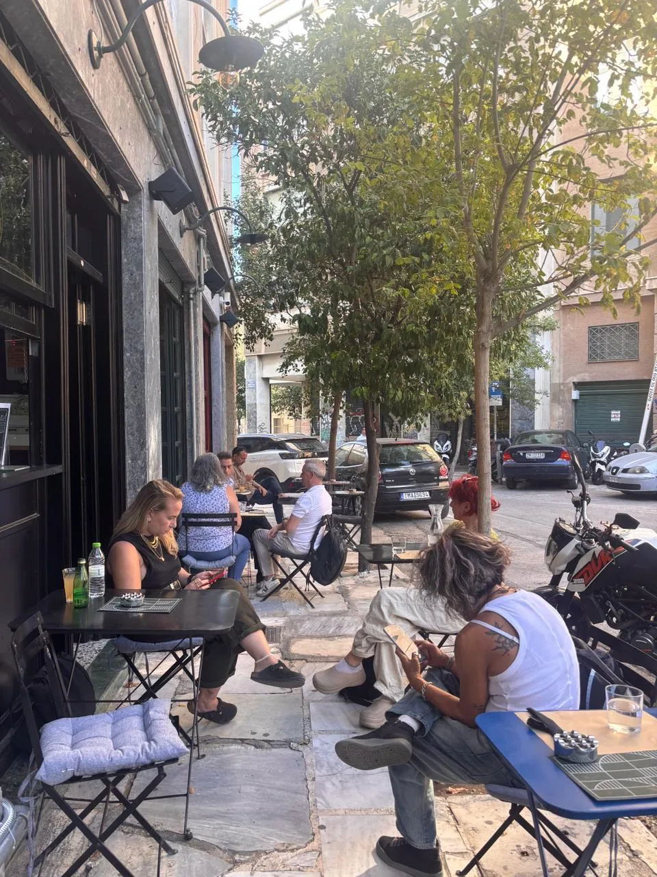Guests at the tables along the pavement, blue cushions on the chairs