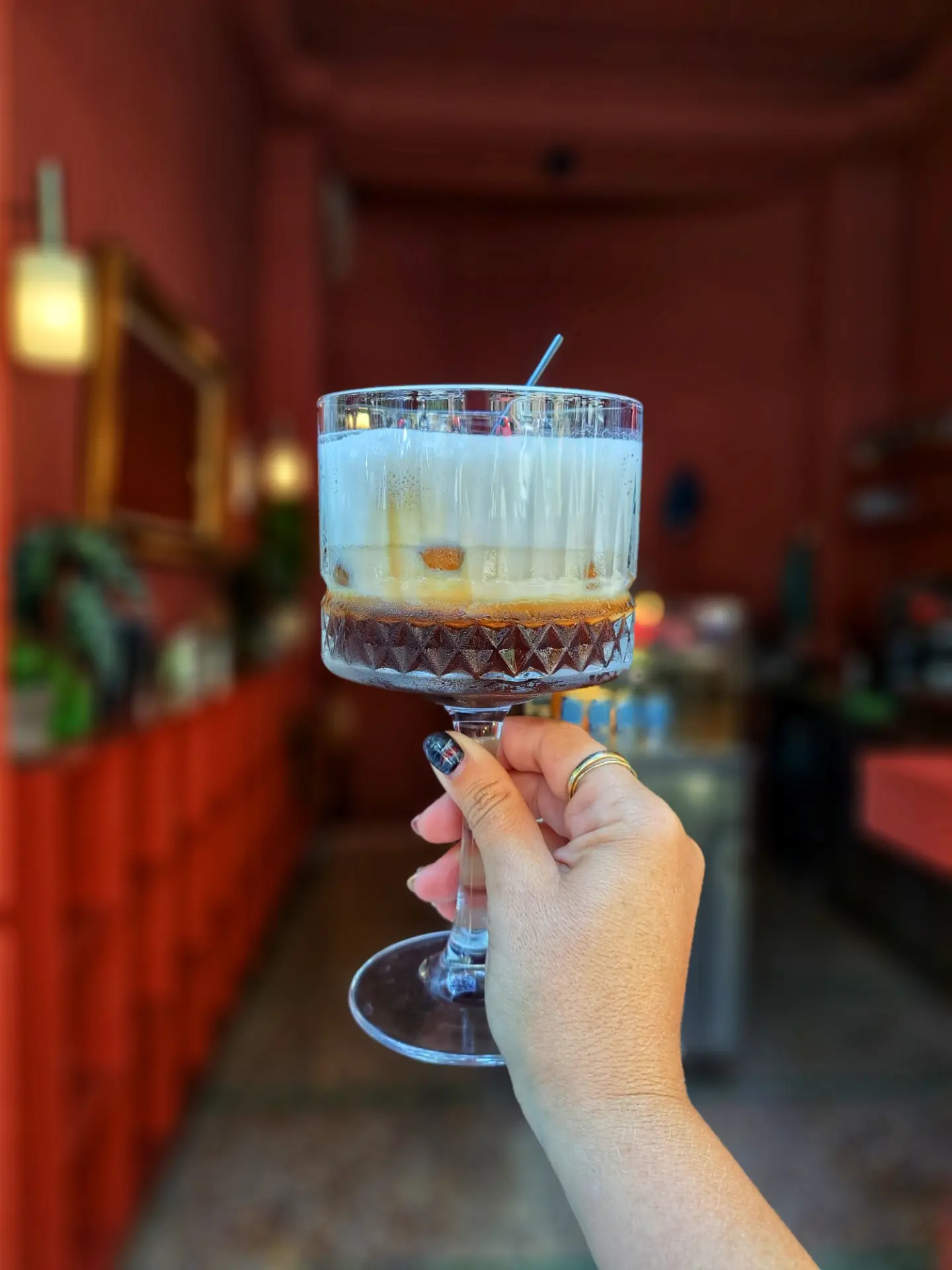 An iced latte held up in a coupe glass