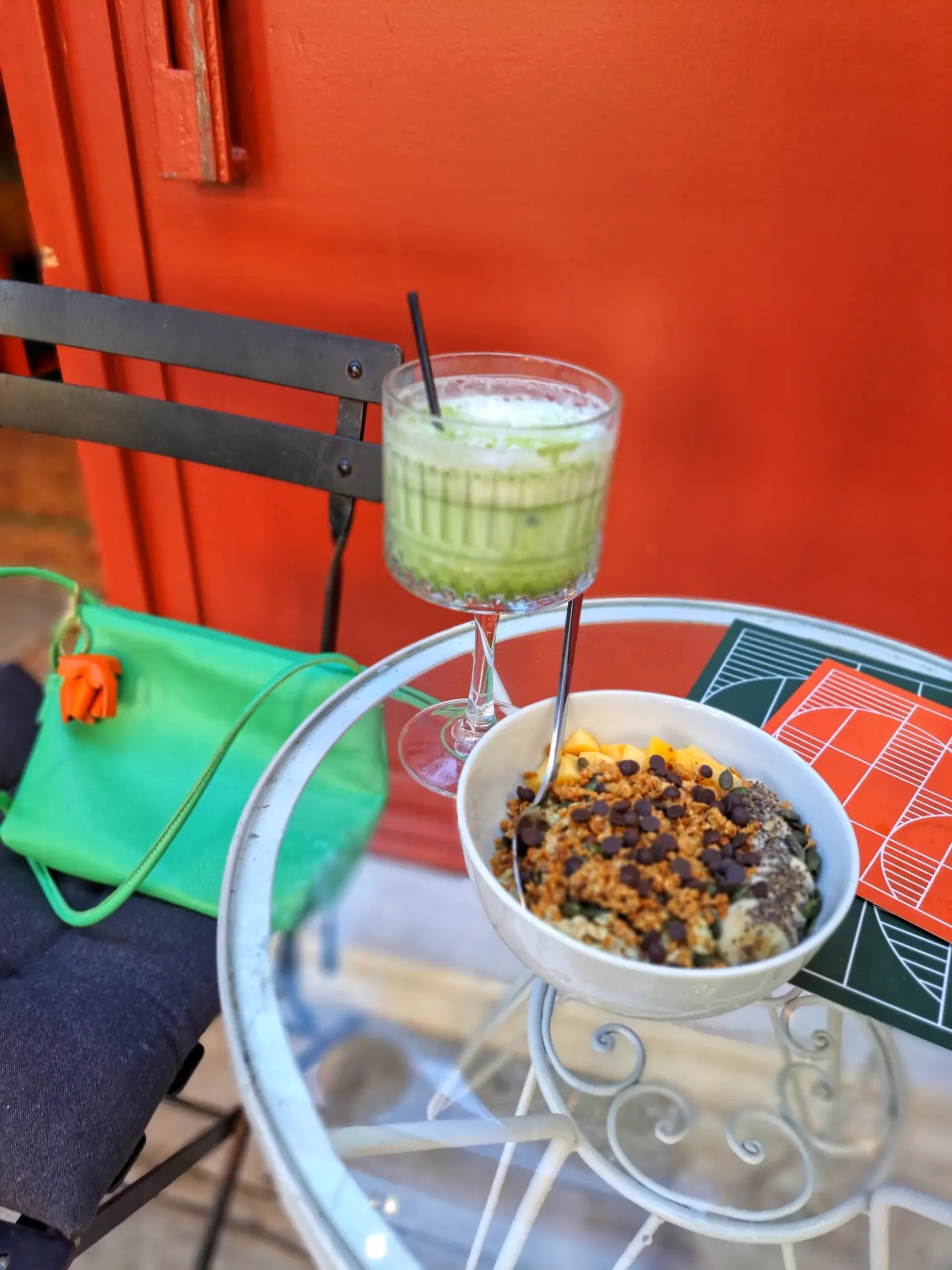 A granola bowl next to an iced matcha, seen from above